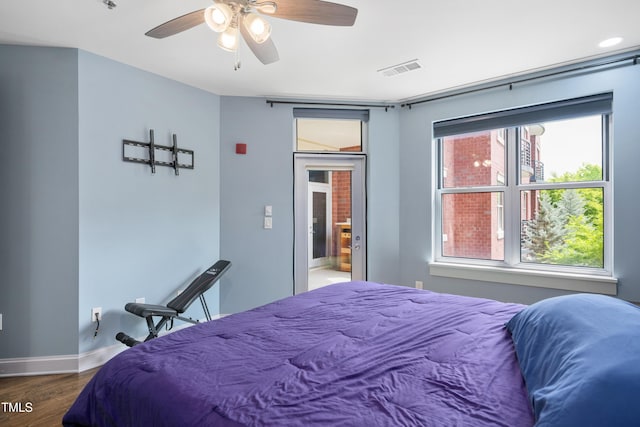 bedroom with baseboards, a ceiling fan, wood finished floors, and visible vents