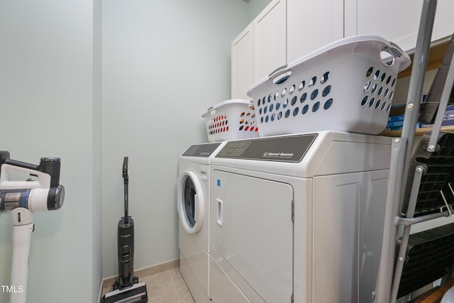 clothes washing area featuring washer and dryer, baseboards, light tile patterned floors, and cabinet space