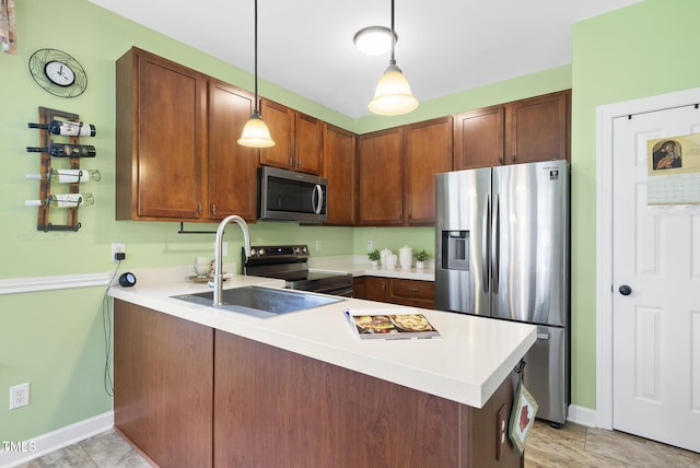kitchen featuring stainless steel appliances, a peninsula, a sink, and baseboards