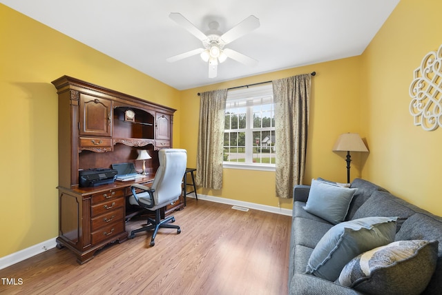 office space with light wood-style flooring, a ceiling fan, and baseboards
