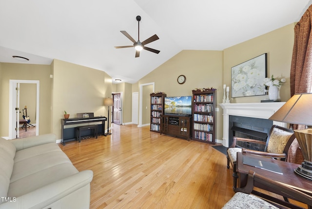 living area with a ceiling fan, wood finished floors, lofted ceiling, a fireplace, and baseboards