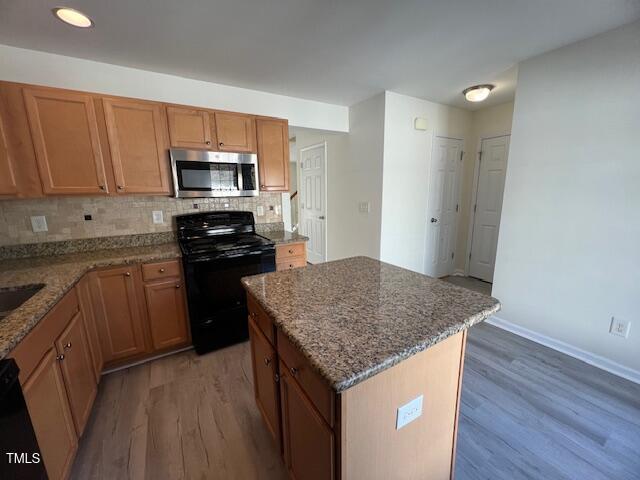 8013 River Water Ct, Raleigh, NC 27616 - kitchen with light wood-style flooring, stainless steel microwave, tasteful backsplash, and black range with gas stovetop
