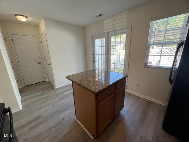 8013 River Water Ct, Raleigh, NC 27616 - kitchen featuring a center island, wood finished floors, freestanding refrigerator, and a wealth of natural light