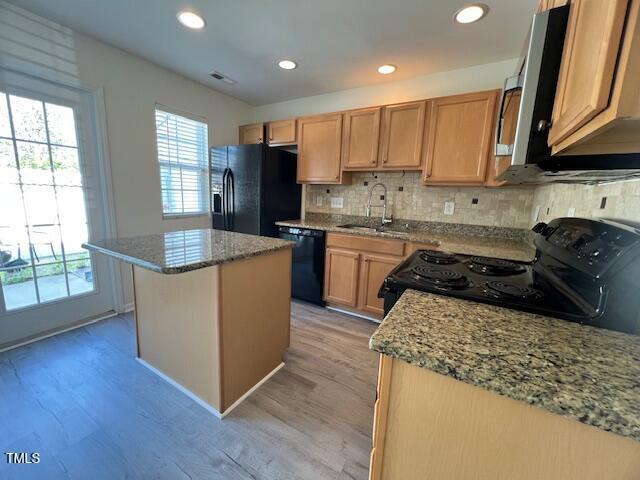 8013 River Water Ct, Raleigh, NC 27616 - kitchen with light wood-style flooring, black appliances, a center island, a sink, and decorative backsplash