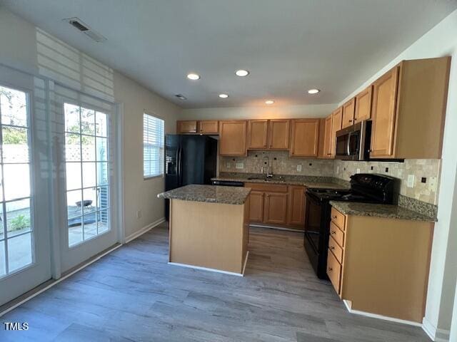 8013 River Water Ct, Raleigh, NC 27616 - kitchen featuring light wood-type flooring, backsplash, a kitchen island, visible vents, and black appliances