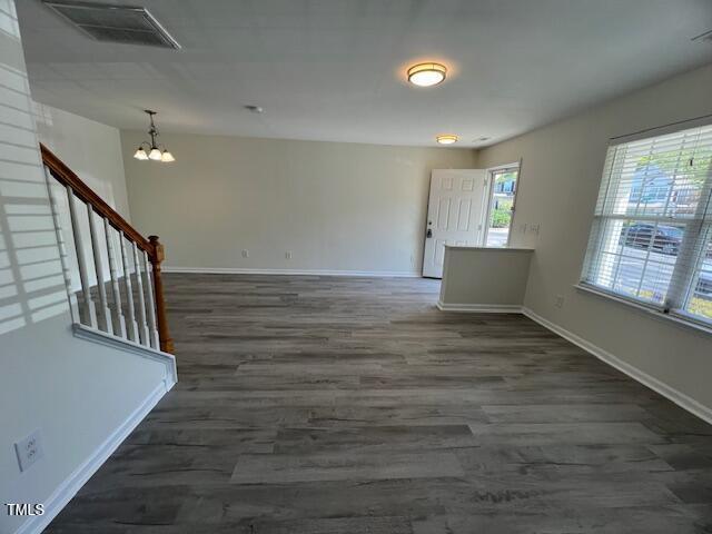 8013 River Water Ct, Raleigh, NC 27616 - empty room featuring stairs, baseboards, an inviting chandelier, and wood finished floors