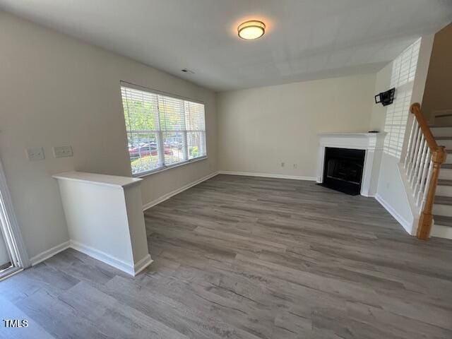 8013 River Water Ct, Raleigh, NC 27616 - unfurnished living room featuring stairway, a fireplace with flush hearth, baseboards, and wood finished floors