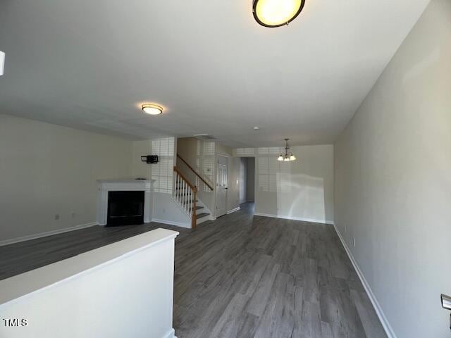 8013 River Water Ct, Raleigh, NC 27616 - unfurnished living room featuring baseboards, an inviting chandelier, a fireplace, stairs, and wood finished floors