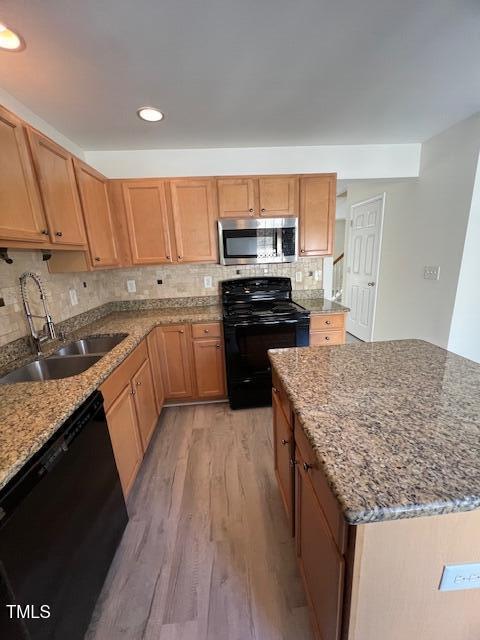 8013 River Water Ct, Raleigh, NC 27616 - kitchen featuring backsplash, black appliances, light stone countertops, light wood-style floors, and a sink