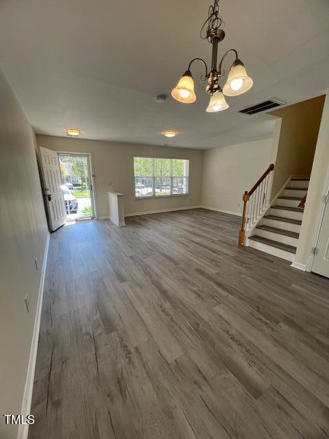 8013 River Water Ct, Raleigh, NC 27616 - unfurnished living room with visible vents, baseboards, stairway, and wood finished floors