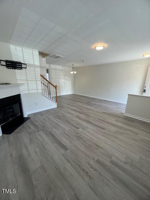 8013 River Water Ct, Raleigh, NC 27616 - unfurnished living room featuring a fireplace with flush hearth, wood finished floors, and baseboards