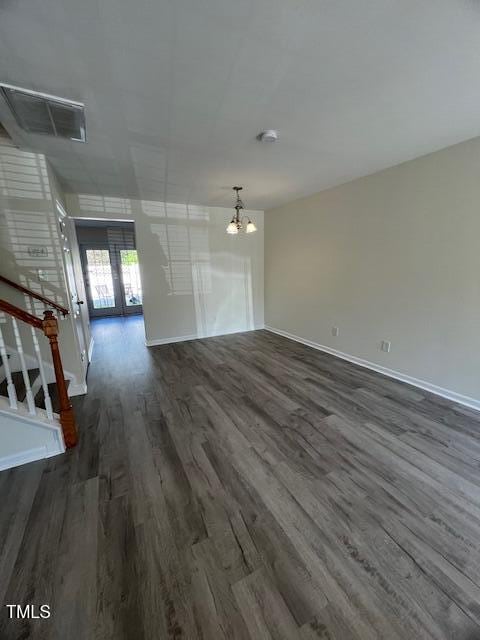 8013 River Water Ct, Raleigh, NC 27616 - unfurnished living room with dark wood-type flooring, visible vents, a chandelier, stairs, and baseboards