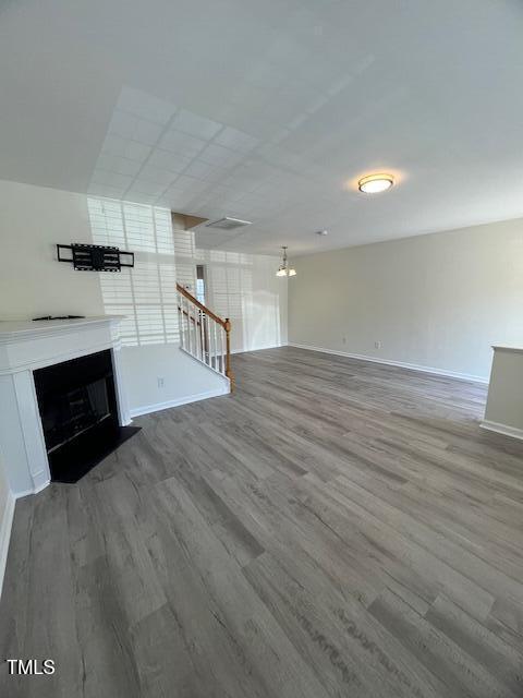 8013 River Water Ct, Raleigh, NC 27616 - unfurnished living room featuring a fireplace with flush hearth, wood finished floors, and baseboards