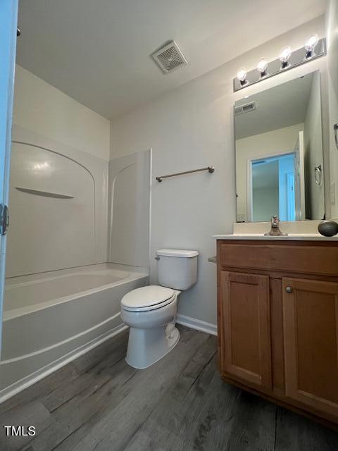8013 River Water Ct, Raleigh, NC 27616 - full bathroom with shower / bathtub combination, vanity, visible vents, toilet, and wood finished floors