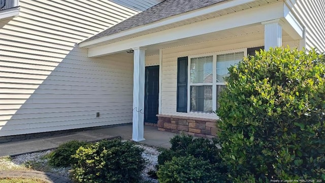 view of side of home with a porch and a shingled roof