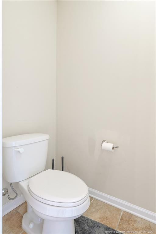 bathroom with baseboards, tile patterned flooring, and toilet