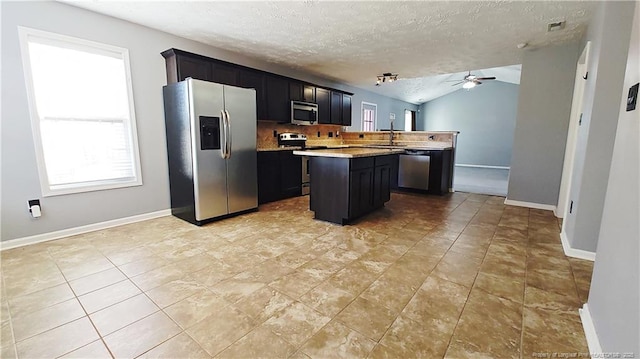 1221 Piping Plover Ct, Fayetteville, NC 28306 - kitchen with appliances with stainless steel finishes, a ceiling fan, a center island, light countertops, and dark cabinetry
