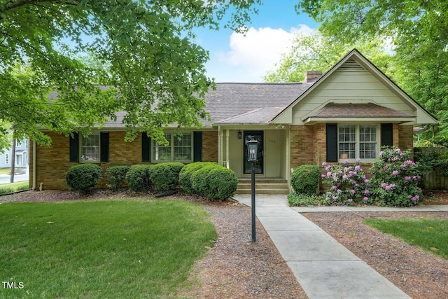 view of front of home featuring brick siding, a shingled roof, a front lawn, and a chimney