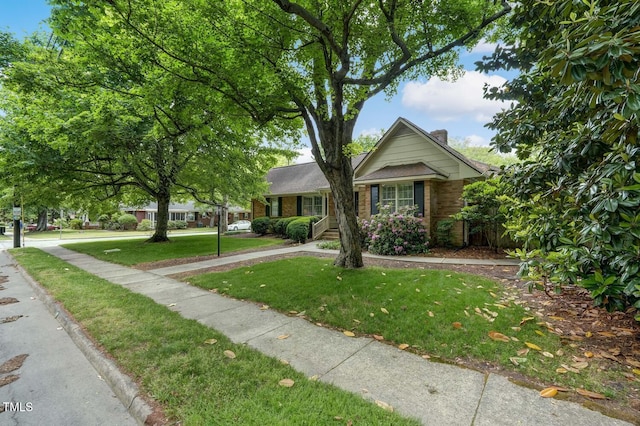 view of front of property featuring brick siding, a front lawn, and a chimney
