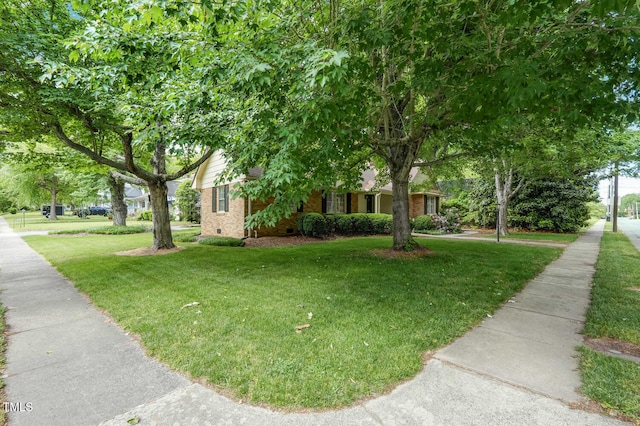 view of property hidden behind natural elements with a front yard, crawl space, and brick siding