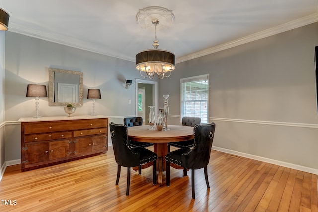 dining area featuring a chandelier, light wood-style flooring, crown molding, and baseboards