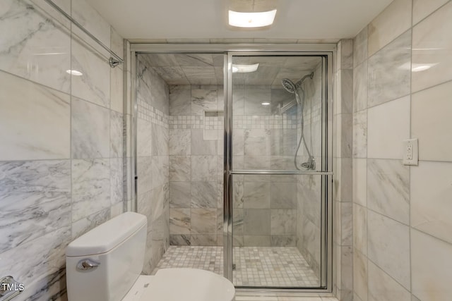 bathroom with toilet, a shower stall, and tile walls