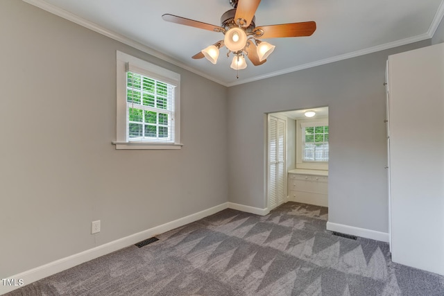 unfurnished bedroom featuring multiple windows, baseboards, carpet flooring, ornamental molding, and ceiling fan