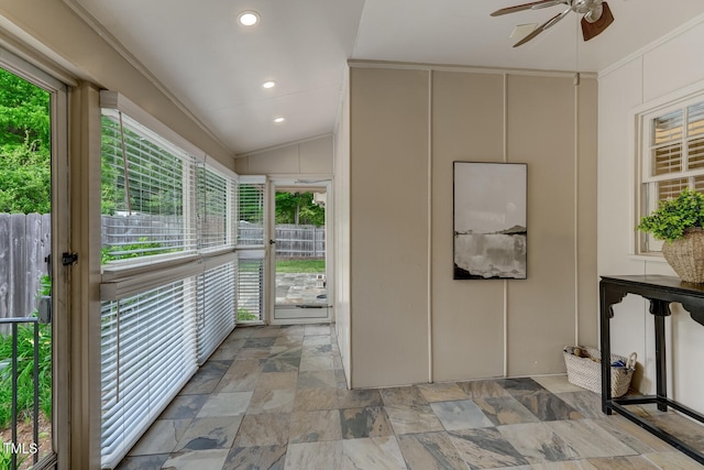 corridor with vaulted ceiling, light stone finish flooring, and a decorative wall