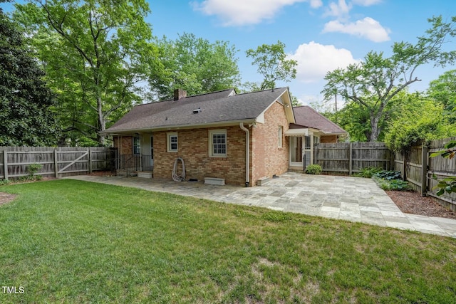 rear view of property with a patio, brick siding, a chimney, and a shingled roof