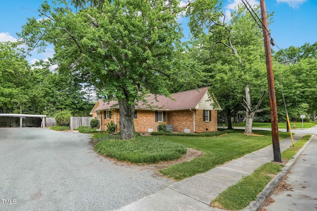 view of front of house featuring brick siding, gravel driveway, and a carport