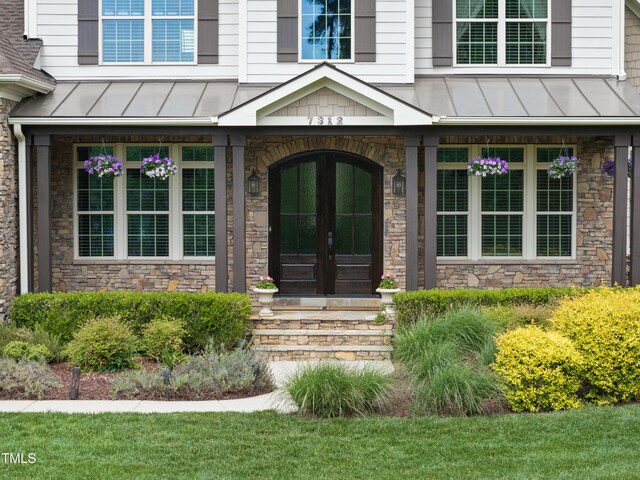 view of exterior entry featuring a standing seam roof, french doors, and stone siding