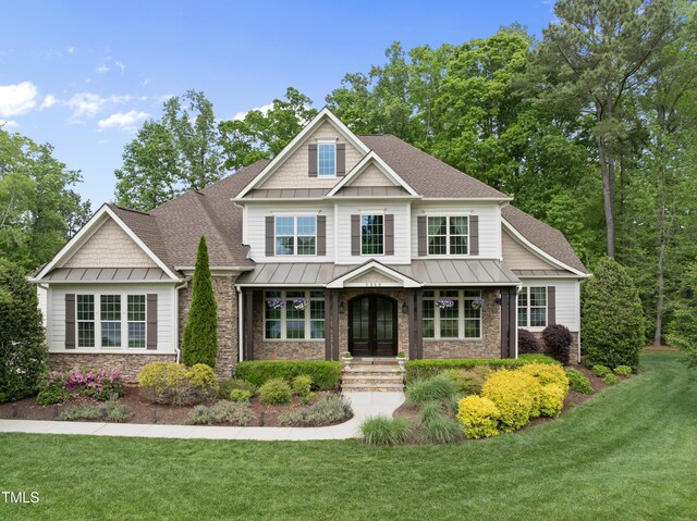 craftsman-style home featuring a shingled roof, a front lawn, stone siding, and a standing seam roof