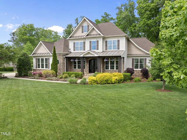 craftsman house with a porch, roof with shingles, a standing seam roof, and stone siding
