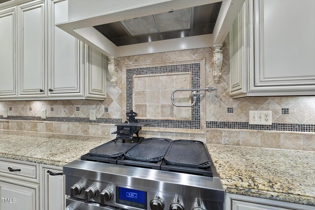 kitchen with a wood stove, ventilation hood, light stone countertops, and backsplash