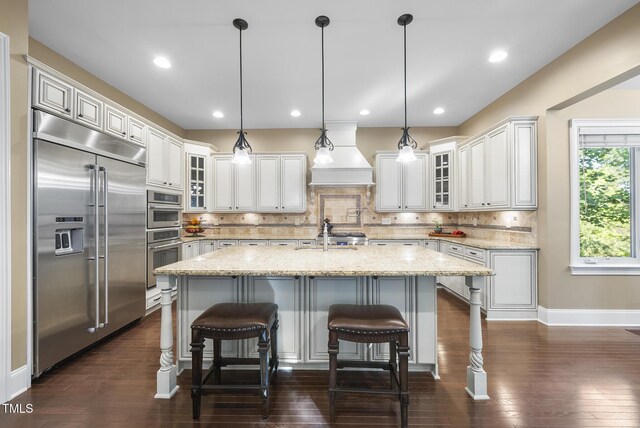 kitchen featuring backsplash, stainless steel appliances, dark wood-type flooring, and an island with sink