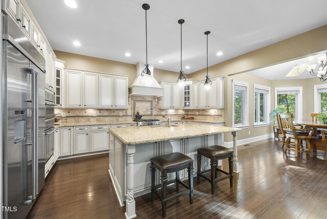 kitchen with light stone counters, decorative backsplash, stainless steel appliances, and dark wood-style flooring