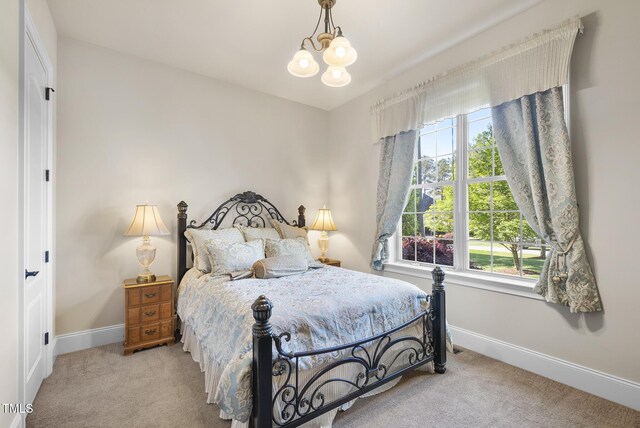 carpeted bedroom featuring baseboards and a chandelier