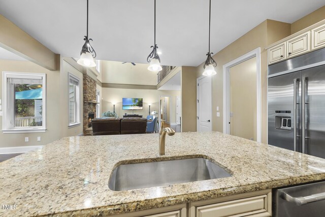 kitchen featuring a sink, appliances with stainless steel finishes, light stone countertops, and open floor plan