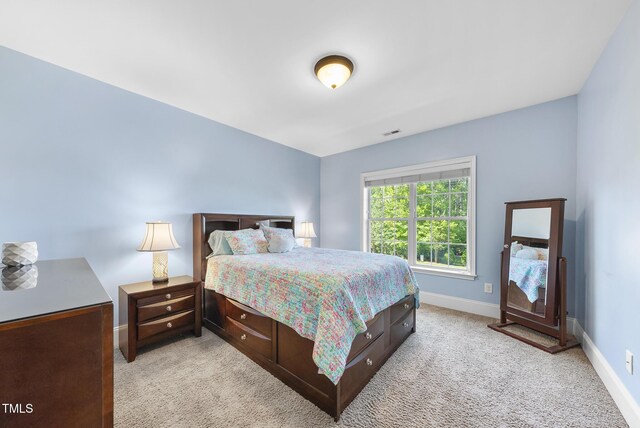 bedroom with baseboards, visible vents, and light colored carpet