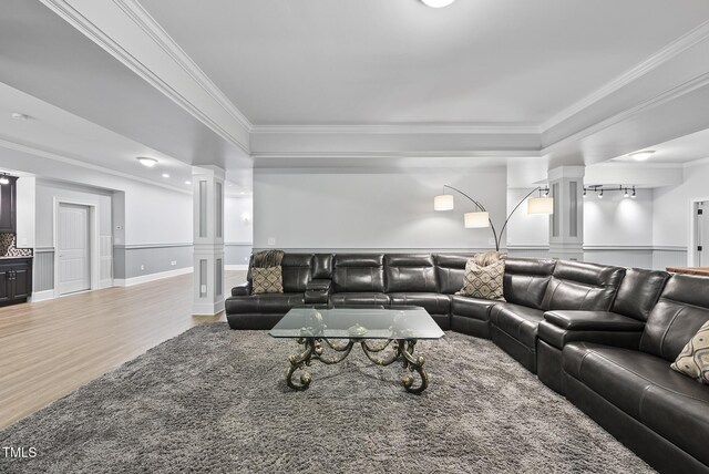 living area featuring a wainscoted wall, ornamental molding, ornate columns, and wood finished floors