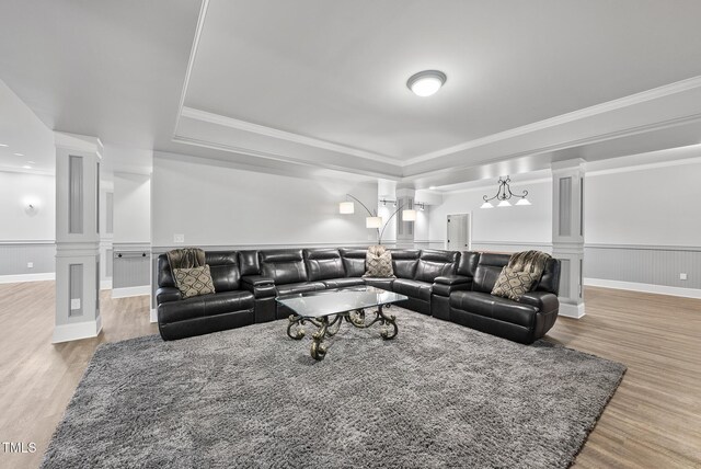 living room with a raised ceiling, a wainscoted wall, decorative columns, and wood finished floors