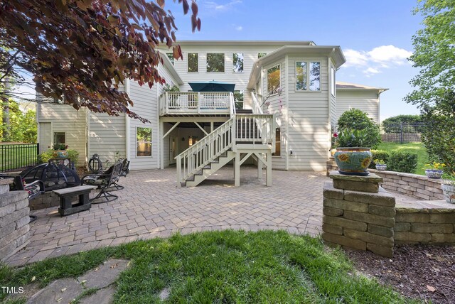 rear view of property featuring fence, a wooden deck, stairs, and a patio area