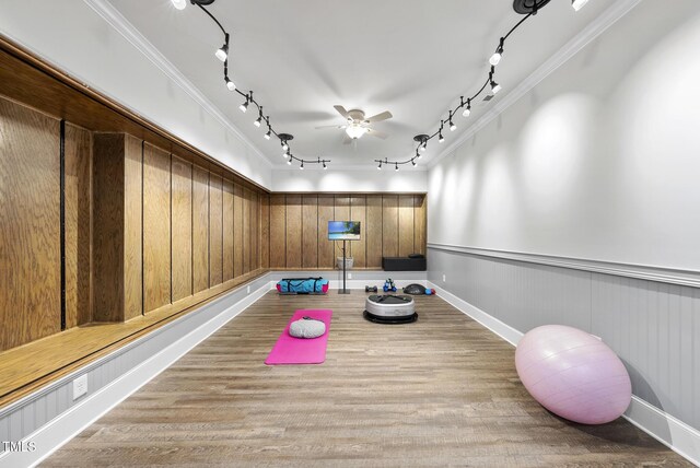 exercise area featuring crown molding, ceiling fan, rail lighting, and wood finished floors