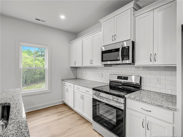 114 Kingwood Dr, Lillington, NC 27546 - kitchen with white cabinetry, visible vents, stainless steel appliances, light wood finished floors, and backsplash
