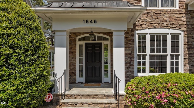 view of exterior entry with a standing seam roof, metal roof, and stone siding