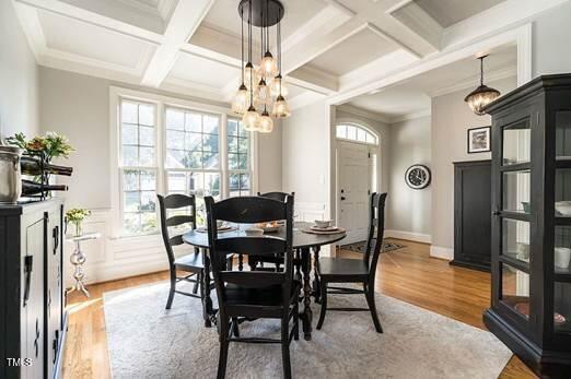 dining room featuring a chandelier, ornamental molding, coffered ceiling, and wood finished floors