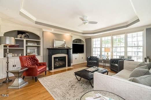 living room featuring a tray ceiling, crown molding, and ceiling fan