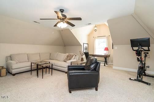 living room featuring a ceiling fan, visible vents, lofted ceiling, and carpet