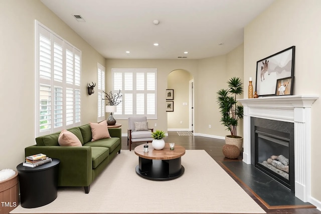 7229 Terregles Dr, Raleigh, NC 27617 - living room featuring recessed lighting, arched walkways, baseboards, a fireplace with flush hearth, and dark wood-type flooring