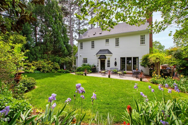 rear view of property with a patio area, a chimney, and a yard